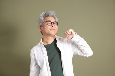 Doğu Asyalı bir işadamının yarım vücut portresi. Koyu yeşil bir arka planda izole edilmiş. Stüdyoda çekilmiş..