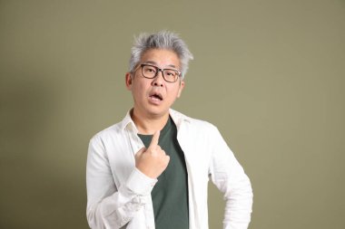 Doğu Asyalı bir işadamının yarım vücut portresi. Koyu yeşil bir arka planda izole edilmiş. Stüdyoda çekilmiş..