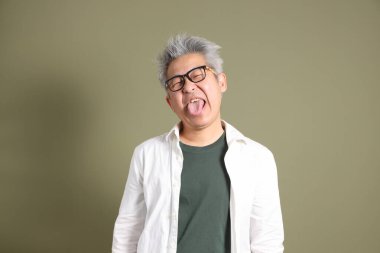 Doğu Asyalı bir işadamının yarım vücut portresi. Koyu yeşil bir arka planda izole edilmiş. Stüdyoda çekilmiş..