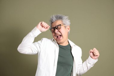 Doğu Asyalı bir işadamının yarım vücut portresi. Koyu yeşil bir arka planda izole edilmiş. Stüdyoda çekilmiş..