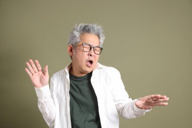 Doğu Asyalı bir işadamının yarım vücut portresi. Koyu yeşil bir arka planda izole edilmiş. Stüdyoda çekilmiş..