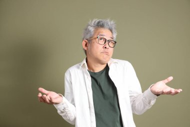 Doğu Asyalı bir işadamının yarım vücut portresi. Koyu yeşil bir arka planda izole edilmiş. Stüdyoda çekilmiş..