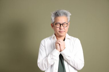 Doğu Asyalı bir işadamının yarım vücut portresi. Koyu yeşil bir arka planda izole edilmiş. Stüdyoda çekilmiş..