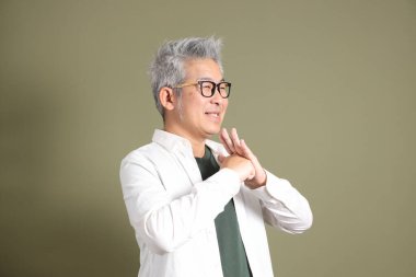 Doğu Asyalı bir işadamının yarım vücut portresi. Koyu yeşil bir arka planda izole edilmiş. Stüdyoda çekilmiş..