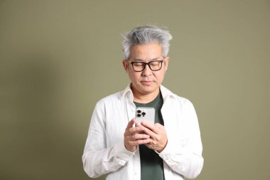 Doğu Asyalı bir işadamının yarım vücut portresi. Koyu yeşil bir arka planda izole edilmiş. Stüdyoda çekilmiş..