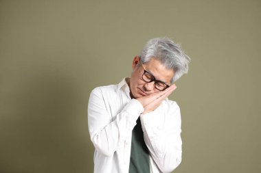 Doğu Asyalı bir işadamının yarım vücut portresi. Koyu yeşil bir arka planda izole edilmiş. Stüdyoda çekilmiş..