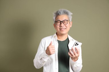 Doğu Asyalı bir işadamının yarım vücut portresi. Koyu yeşil bir arka planda izole edilmiş. Stüdyoda çekilmiş..