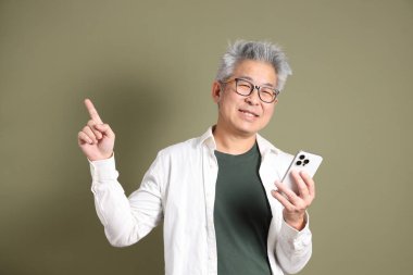 Doğu Asyalı bir işadamının yarım vücut portresi. Koyu yeşil bir arka planda izole edilmiş. Stüdyoda çekilmiş..