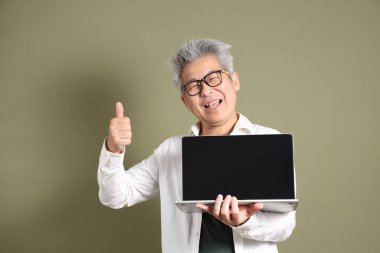 Doğu Asyalı bir işadamının yarım vücut portresi. Koyu yeşil bir arka planda izole edilmiş. Stüdyoda çekilmiş..