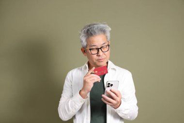 Doğu Asyalı bir işadamının yarım vücut portresi. Koyu yeşil bir arka planda izole edilmiş. Stüdyoda çekilmiş..