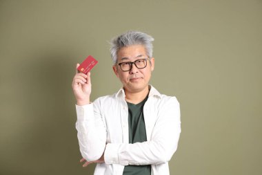 Doğu Asyalı bir işadamının yarım vücut portresi. Koyu yeşil bir arka planda izole edilmiş. Stüdyoda çekilmiş..