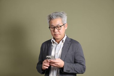 Doğu Asyalı bir işadamının yarım vücut portresi. Koyu yeşil bir arka planda izole edilmiş. Stüdyoda çekilmiş..