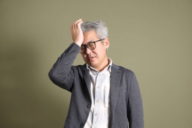 Doğu Asyalı bir işadamının yarım vücut portresi. Koyu yeşil bir arka planda izole edilmiş. Stüdyoda çekilmiş..