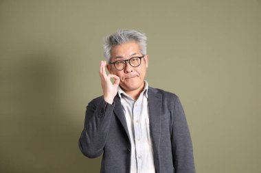 Doğu Asyalı bir işadamının yarım vücut portresi. Koyu yeşil bir arka planda izole edilmiş. Stüdyoda çekilmiş..