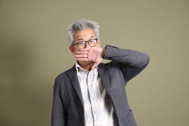 Doğu Asyalı bir işadamının yarım vücut portresi. Koyu yeşil bir arka planda izole edilmiş. Stüdyoda çekilmiş..