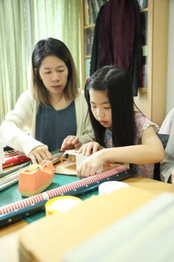 Doğu Asyalı aileler kızlarına yardım ediyor ve yeni yıl hediyelerini nasıl paketleyeceklerini öğretiyorlar..