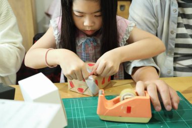 Doğu Asyalı aileler kızlarına yardım ediyor ve yeni yıl hediyelerini nasıl paketleyeceklerini öğretiyorlar..