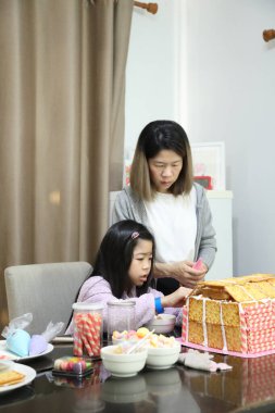 Doğu Asyalı anne yaklaşan parti için kızının yardımıyla ev ekmeğini pişiriyor ve dekore ediyor..