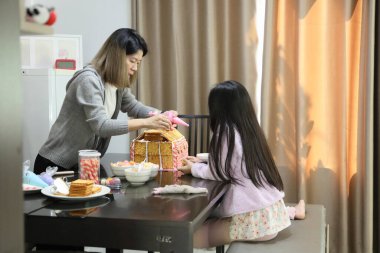 Doğu Asyalı anne yaklaşan parti için kızının yardımıyla ev ekmeğini pişiriyor ve dekore ediyor..