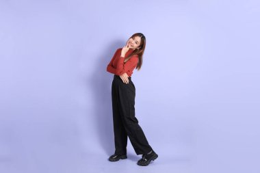 Mor arka planda dikilen, günlük giysiler içindeki genç Güneydoğu Asyalı kadın..