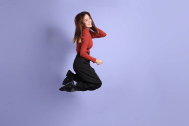 Mor arka planda dikilen, günlük giysiler içindeki genç Güneydoğu Asyalı kadın..