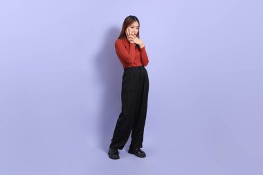 Mor arka planda dikilen, günlük giysiler içindeki genç Güneydoğu Asyalı kadın..