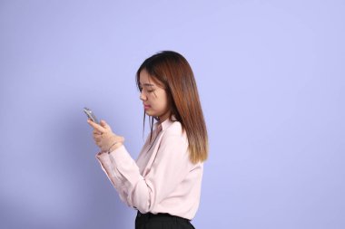 Mor arka planda duran iş elbiseli Güneydoğu Asyalı genç bir kadın..