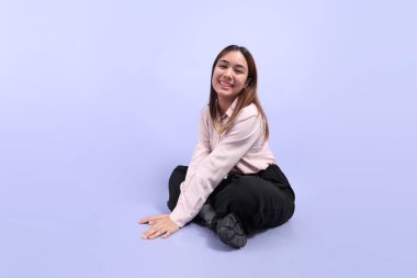 Mor arka planda duran iş elbiseli Güneydoğu Asyalı genç bir kadın..