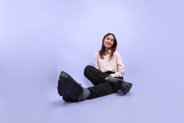 Mor arka planda duran iş elbiseli Güneydoğu Asyalı genç bir kadın..