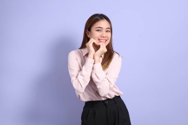 Mor arka planda duran iş elbiseli Güneydoğu Asyalı genç bir kadın..