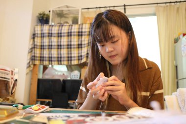 Doğu Asyalı kadın oturma odasında plastik bir oyuncak monte ediyor..