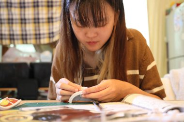 Doğu Asyalı kadın oturma odasında plastik bir oyuncak monte ediyor..