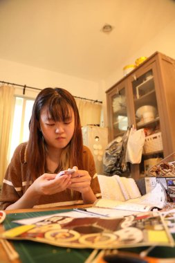 Doğu Asyalı kadın oturma odasında plastik bir oyuncak monte ediyor..