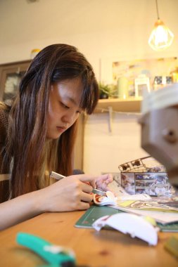 Doğu Asyalı kadın oturma odasında plastik bir oyuncak monte ediyor..