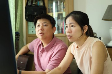 Doğu Asyalı adam, karısı için gitar çalarken, karısı da onun çalması için müzik seçiyor..