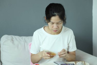 Doğu Asyalı bir kadın akıllı telefon ekran koruyucusu için posta paketini kontrol ediyor ve akıllı telefonuna uyguluyor..