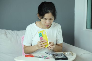 Doğu Asyalı bir kadın akıllı telefon ekran koruyucusu için posta paketini kontrol ediyor ve akıllı telefonuna uyguluyor..