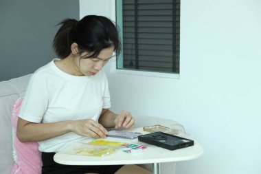 Doğu Asyalı bir kadın akıllı telefon ekran koruyucusu için posta paketini kontrol ediyor ve akıllı telefonuna uyguluyor..