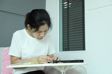 Doğu Asyalı bir kadın akıllı telefon ekran koruyucusu için posta paketini kontrol ediyor ve akıllı telefonuna uyguluyor..