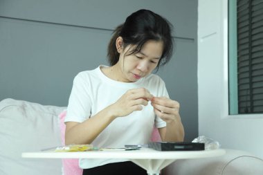 Doğu Asyalı bir kadın akıllı telefon ekran koruyucusu için posta paketini kontrol ediyor ve akıllı telefonuna uyguluyor..