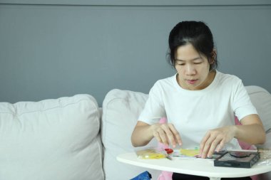 Doğu Asyalı bir kadın akıllı telefon ekran koruyucusu için posta paketini kontrol ediyor ve akıllı telefonuna uyguluyor..