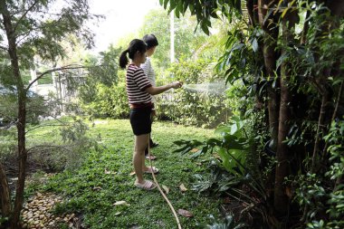 Doğu Asyalı çift evlerinin etrafındaki bitkileri bahçeleyip suluyor..