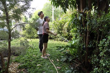 Doğu Asyalı çift evlerinin etrafındaki bitkileri bahçeleyip suluyor..