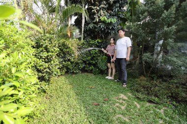 Doğu Asyalı çift evlerinin etrafındaki bitkileri bahçeleyip suluyor..