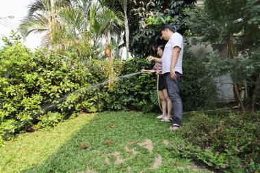 Doğu Asyalı çift evlerinin etrafındaki bitkileri bahçeleyip suluyor..