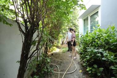 Doğu Asyalı çift evlerinin etrafındaki bitkileri bahçeleyip suluyor..