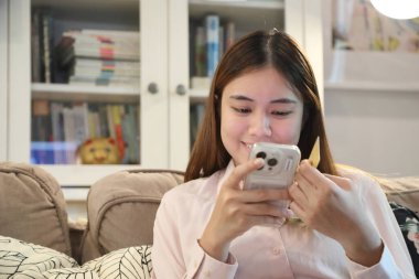 Tatlı Güneydoğu Asyalı kadın akıllı telefonuyla online alışveriş yapmak için kredi kartı kullanıyor..