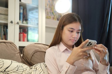 Tatlı Güneydoğu Asyalı kadın akıllı telefonuyla online alışveriş yapmak için kredi kartı kullanıyor..