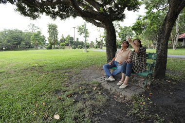 Doğu Asyalı çift parkta oturuyor ve dinleniyorlar..
