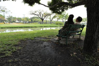 Doğu Asyalı çift parkta oturuyor ve dinleniyorlar..